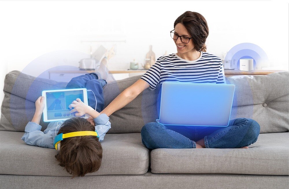 Router D-LINK M60 Aquila PRO AX6000 chłopiec ogląda tablet, kobieta pracuje na laptopie, a w tle router rozsyła sygnał Wi-Fi