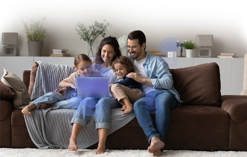 Router D-LINK M60 Aquila PRO AX6000 rodzina oglądająca treści na laptopie, z widocznym efektem wizualnym symbolizującym stabilne połączenie Wi-Fi