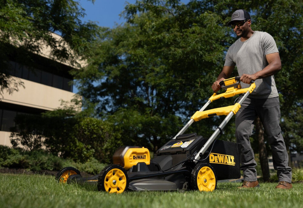 Kosiarka akumulatorowa DEWALT DCMWSP550N-XJ z napędem ogród trawnik osoba kosi trawę w ogrodzie w tle dom drzewa niebo zadbany trawnik koszenie trawy wygoda