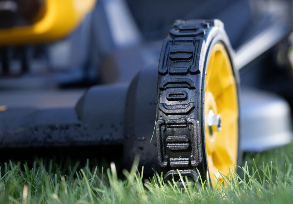 Kosiarka akumulatorowa DEWALT DCMWSP550N-XJ z napędem zbliżenie na przednie koło trawnik amortyzowane gumowe koła stabilność prowadzenia ograniczają przenoszenie drgań na uchwyt lepsza przyczepność do podłoża ułatwia utrzymanie prostego toru jazdy i równą pracę układu tnącego