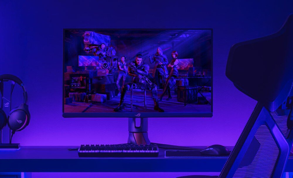 Monitor ASUS ROG Strix XG27ACDNG Monitor na biurku w pokoju oświetlonym niebiesko-fioletowym światłem, z wyświetloną sceną z gry, przedstawiającą cztery postacie w futurystycznym pomieszczeniu; obok słuchawki, klawiatura i krzesło gamingowe, jasność