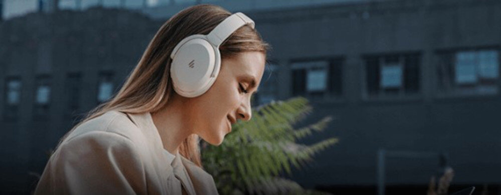 Słuchawki EDIFIER WH700NB Pro ANC z pasmem przenoszenia 20Hz-40kHz, osoba z założonymi słuchawkami nausznymi w plenerze