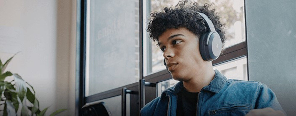 Słuchawki EDIFIER WH700NB Pro ANC z elastycznymi trybami redukcji hałasu, osoba z założonymi słuchawkami nausznymi z telefonem w ręku