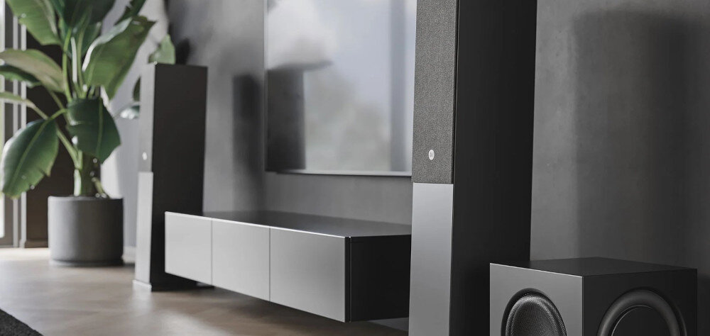 Kolumna AUDIO PRO A48 pilot zdalnego sterowania, aplikacja AudioPro, kolumny stojące obok szafki z subwooferem w pomieszczeniu