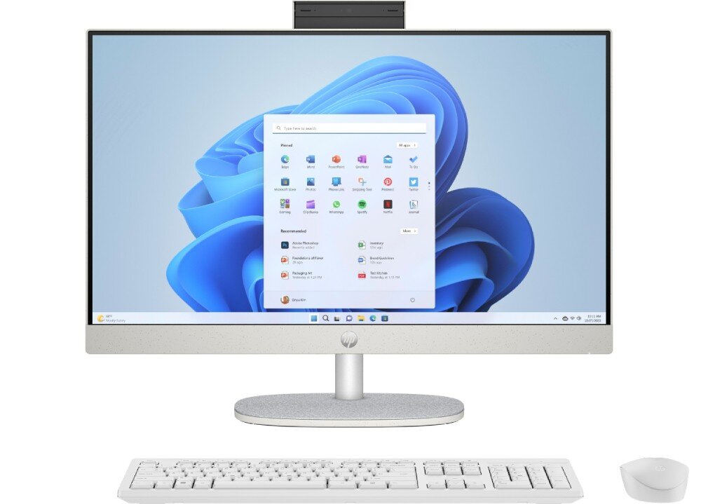 Komputer All in One HP 24-cr0332nw Na obrazie widoczny jest komputer All in One z dużym ekranem, klawiaturą i myszką. Na ekranie wyświetlony jest interfejs systemu Windows 11 z ikonami aplikacji.