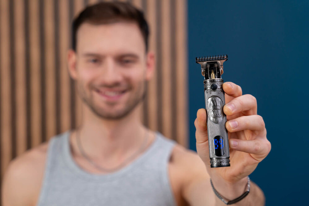 Trymer GÖTZE & JENSEN TR726 Mężczyzna prezentujący ozdobny, metalowy trymer Götze & Jensen TR726 z wyświetlaczem LCD pokazującym stan baterii.