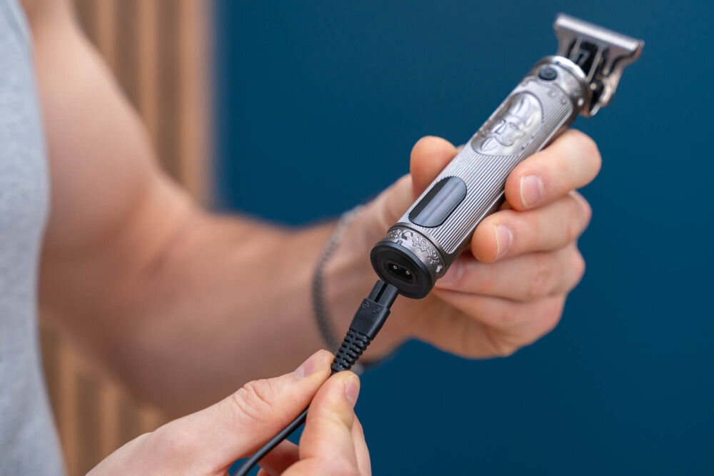 Trymer GÖTZE & JENSEN TR726 Zbliżenie na podłączanie dedykowanego kabla zasilającego do dolnego portu ładowania trymera Götze & Jensen TR726.