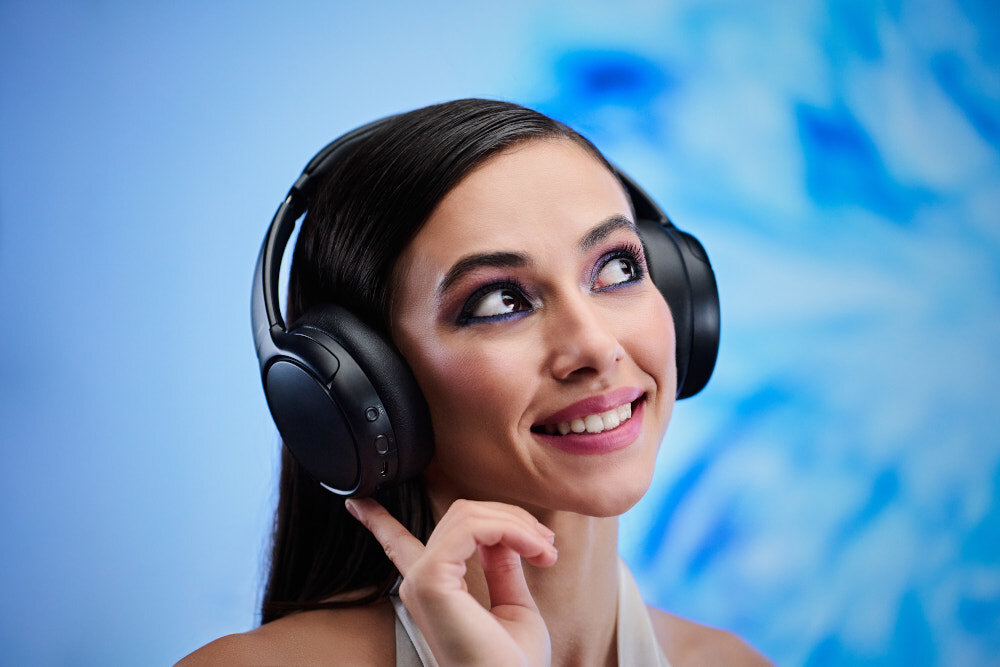 Słuchawki nauszne PANASONIC RB-M600BE-C - Głębia dźwięku bez zakłóceń, czysty dźwięk bez szumów, mikrofon, poduszki, osoba z założonymi słuchawkami nausznymi na błękitnym tle