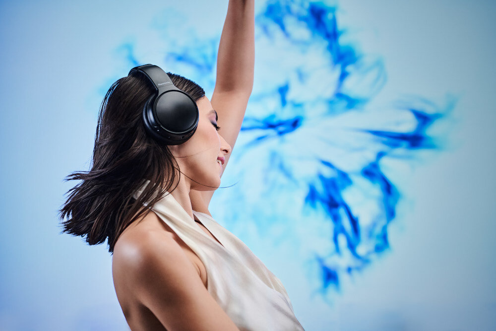 Słuchawki nauszne PANASONIC RB-M600BE-C - Cisza, która daje skupienie, Redukcja szumów, Mikrofony, osoba z założonymi słuchawkami nausznymi na błękitnym tle