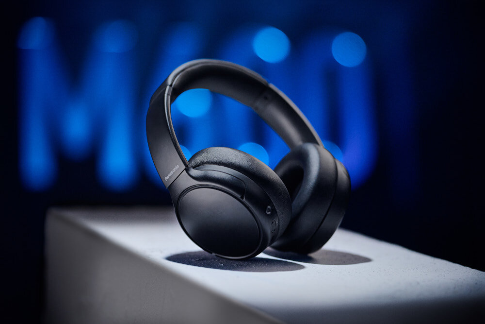 Słuchawki nauszne PANASONIC RB-M600BE-C - Gotowe na długą trasę, Czas pracy do 65 godzin, Szybkie ładowanie w 15 minut - do 6 godzin działania, słuchawki nauszne na białym postumencie na ciemnym tle