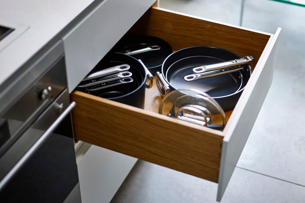 JJ-Patelnia 28cm ze składanym uchwytem Space otwarta półka z kuchni złożone garnki i patelnie srebrne rączki jasne tło średnica 28 cm składany uchwyt ze stali nierdzewnej zajmuje mało miejsca płytkie półki w szafkach ograniczona przestrzeń SwingLock stabilne przymocowanie uchwytu do korpusu funkcjonalność i wygoda