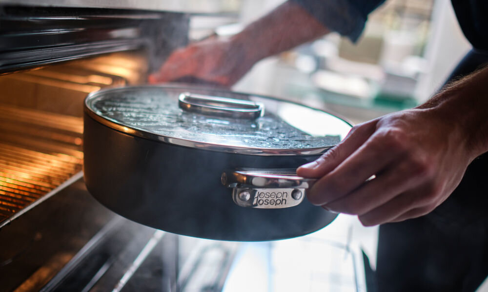 JJ-Garnek niski 28cm ze skł. uchwytami+pokr.Space garnek niebieska powłoka srebrne uchwyty osoba wkłada garnek do piekarnika pokrywka kuchenne tło  szklana pokrywka ze składanym, stalowym uchwytem można używać w piekarniku do max. 200°C możliwość mycia w zmywarce zalecane mycie ręczne dłużej służy zachowanie właściwości 