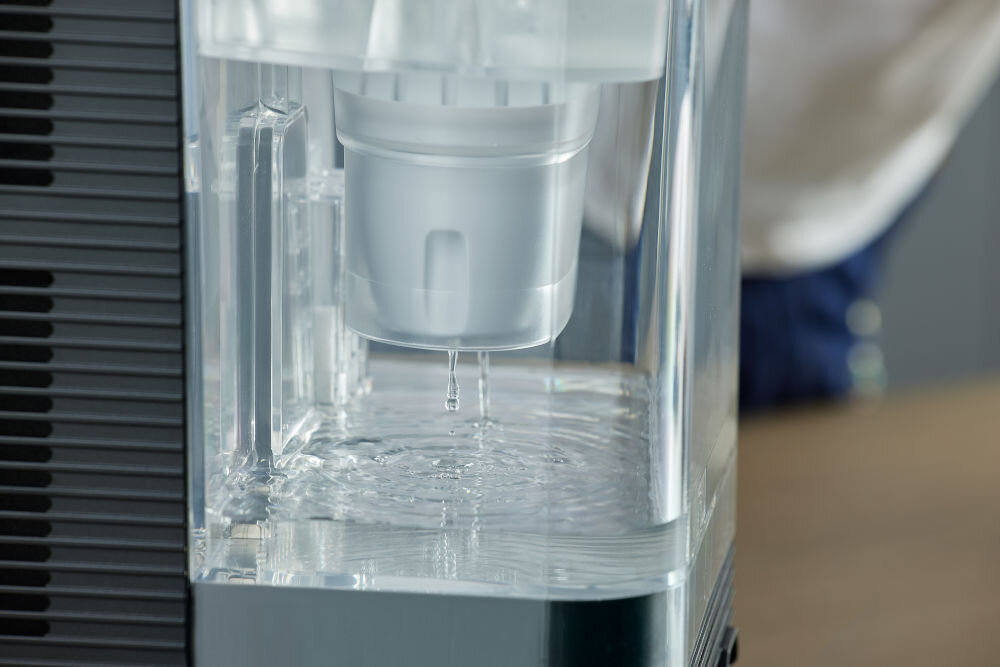 Dyspenser do wody PHILIPS ADD5962BK/10 Zbliżenie na proces filtracji wody w przezroczystym zbiorniku dystrybutora Philips z widocznym wkładem filtrującym.