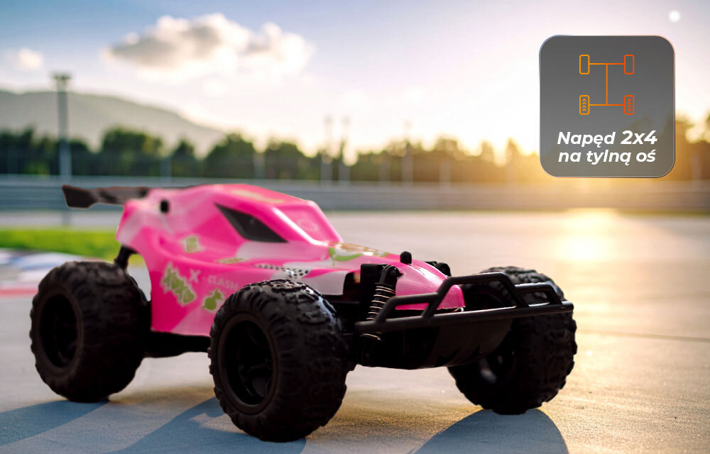 Samochód zdalnie sterowany OVERMAX X-Clash Samochód X-CLASH w różowym malowaniu stojący na torze wyścigowym lub asfalcie. Słońce świeci zza horyzontu. Ikona w prawym rogu informuje o napędzie 2x4 na tylną oś.