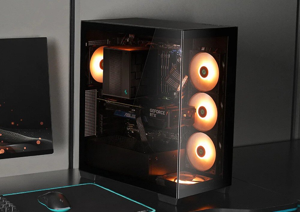 Obudowa DEEPCOOL CG580 4F Czarna obudowa komputerowa middle tower na biurku, z lewej strony widać fragment monitora, a z prawej ściany, wewnątrz podzespoły z pomarańczowym podświetleniem