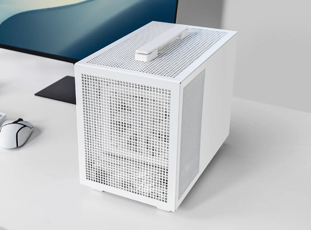 Obudowa DEEPCOOL CH160 Mesh Komputer w białej obudowie stojący na biurku, wyposażony w rączkę do przenoszenia na górnym panelu, z widocznym w tle monitorem i klawiaturą
