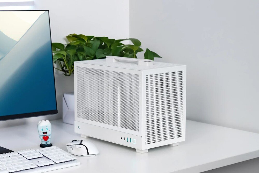 Obudowa DEEPCOOL CH160 Mesh Biała obudowa komputera stojąca na biurku na tle półek z drewnianymi pudełkami, widoczna pod kątem ukazującym front i bok z siatki