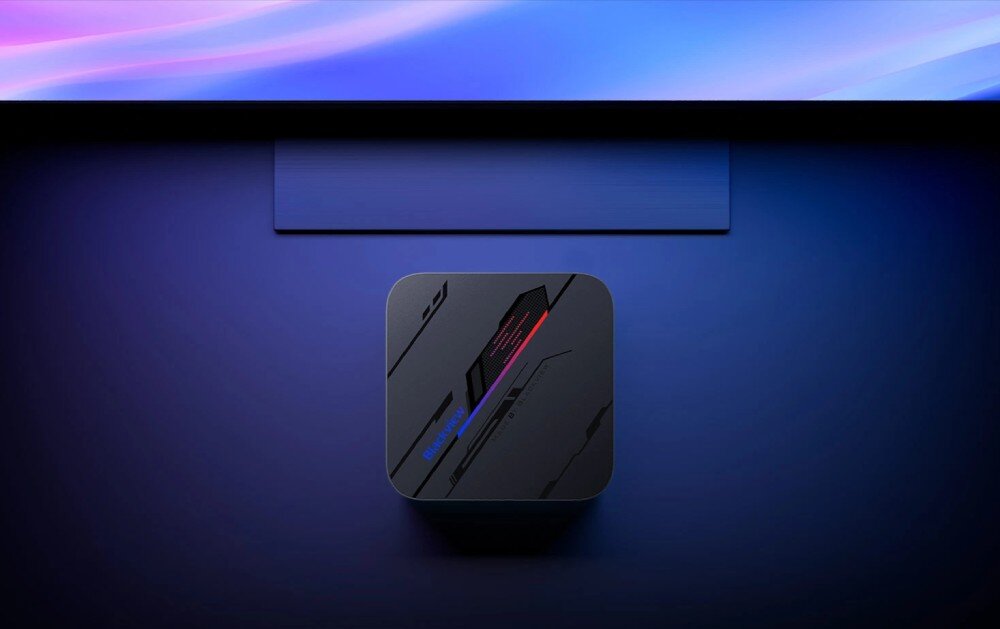 Komputer BLACKVIEW MP100 Widok z góry na komputer mini z podświetleniem w odcieniach niebieskiego i różowego, stojący pod ekranem, obudowa, waga, uchwyt VESA