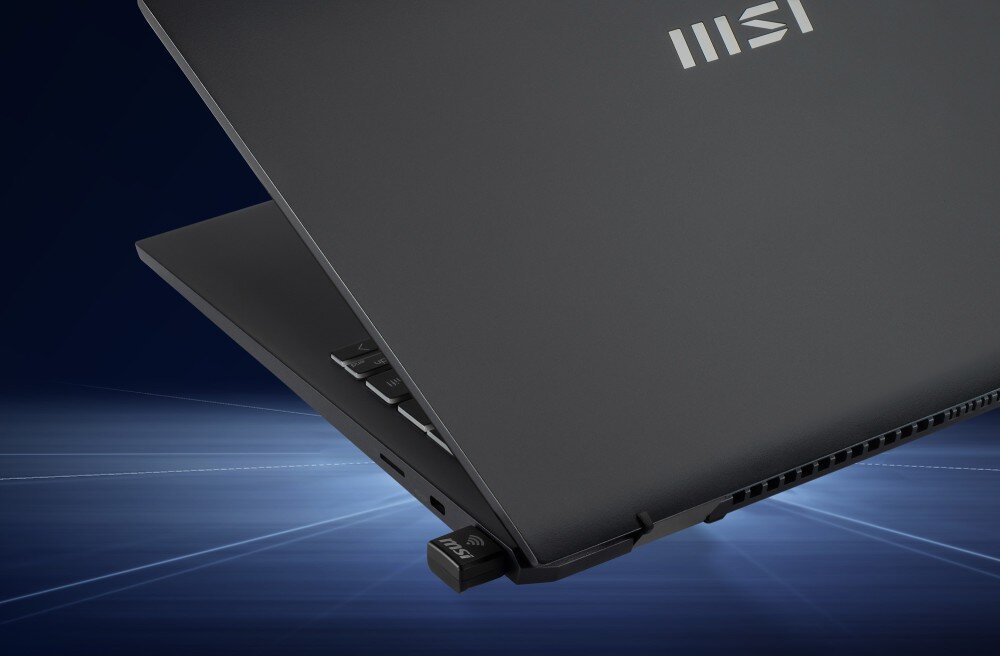 Karta sieciowa MSI AX1800 Nano GUAX18N Widok na krawędź czarnego laptopa z wpiętym w gniazdo małym adapterem sieciowym na tle błękitnych linii świetlnych