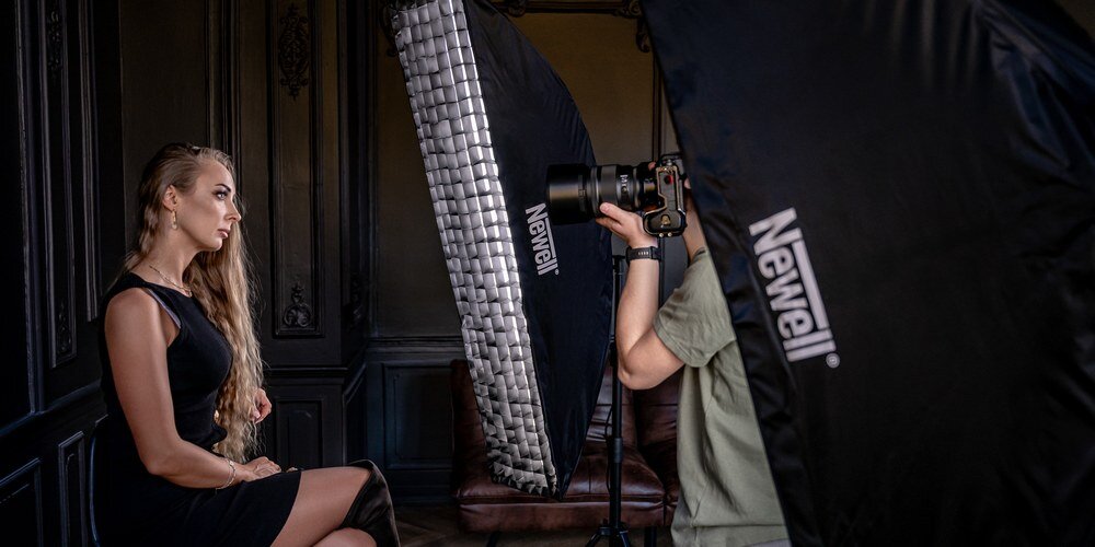 Fotograf wykonuje portret kobiety w studiu z użyciem dwóch softboxów Newell 35×140 cm jako źródeł światła