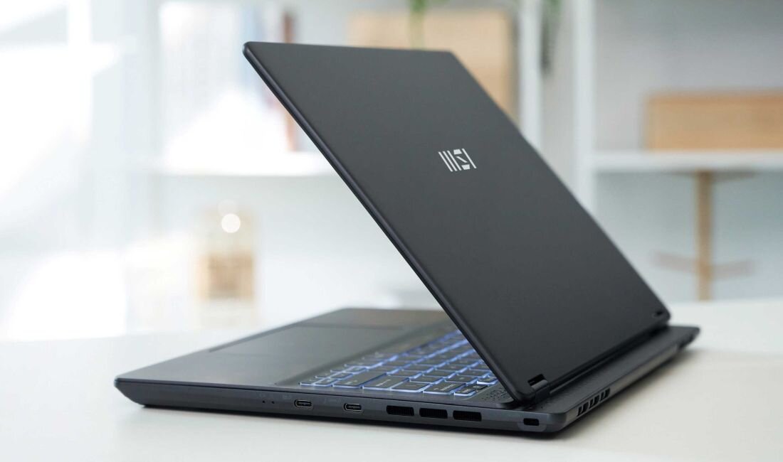 Zbliżenie na system chłodzenia Cooler Boost 3 w laptopie MSI Prestige 14 AI Studio – dwa wentylatory i podwójne ciepłowody, widoczne wyloty powietrza po lewej stronie obudowy, podświetlana klawiatura. - Podwójny system chłodzenia Cooler Boost 3