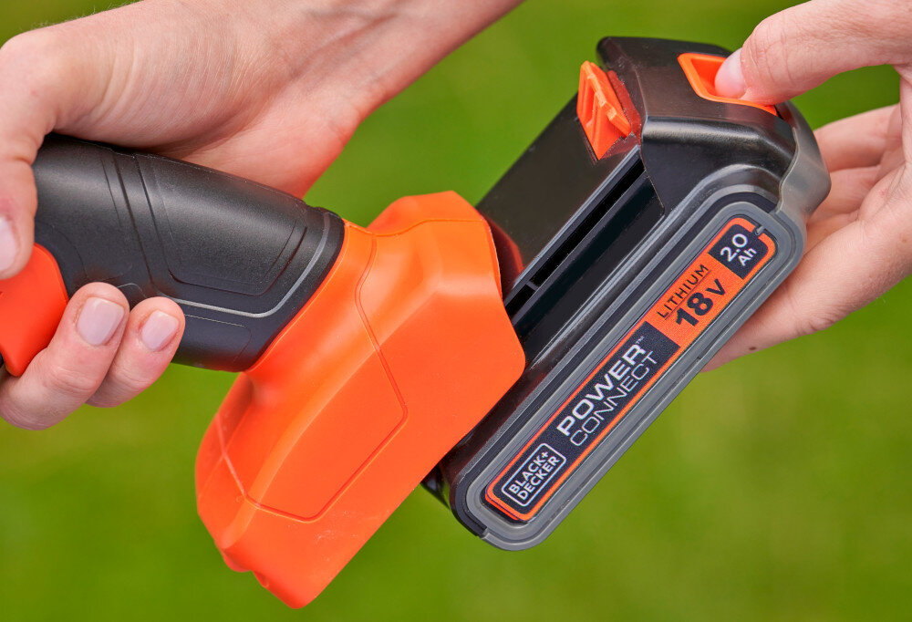 Nożyce do trawy BLACK&DECKER BCSS18B-XJ 200mm 18V akumulatorowe osoba wkłada akumulator do nożyc zielone tło współpracuje z systemem BLACK+DECKER POWER CONNECT 18 V możliwość używania jednego akumulatora w wielu narzędziach ograniczasz koszty i liczbę ładowarek swoboda pracy bez kabla łatwe manewrowanie w ogrodzie napięcie 18 V