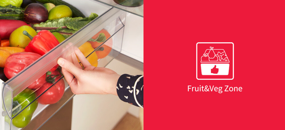 Osoba otwiera szufladę lodówki wypełnioną różnymi warzywami i owocami. Obok znajduje się czerwony panel z ikoną koszyka z owocami i napisem \'Fruit&Veg Zone\'.