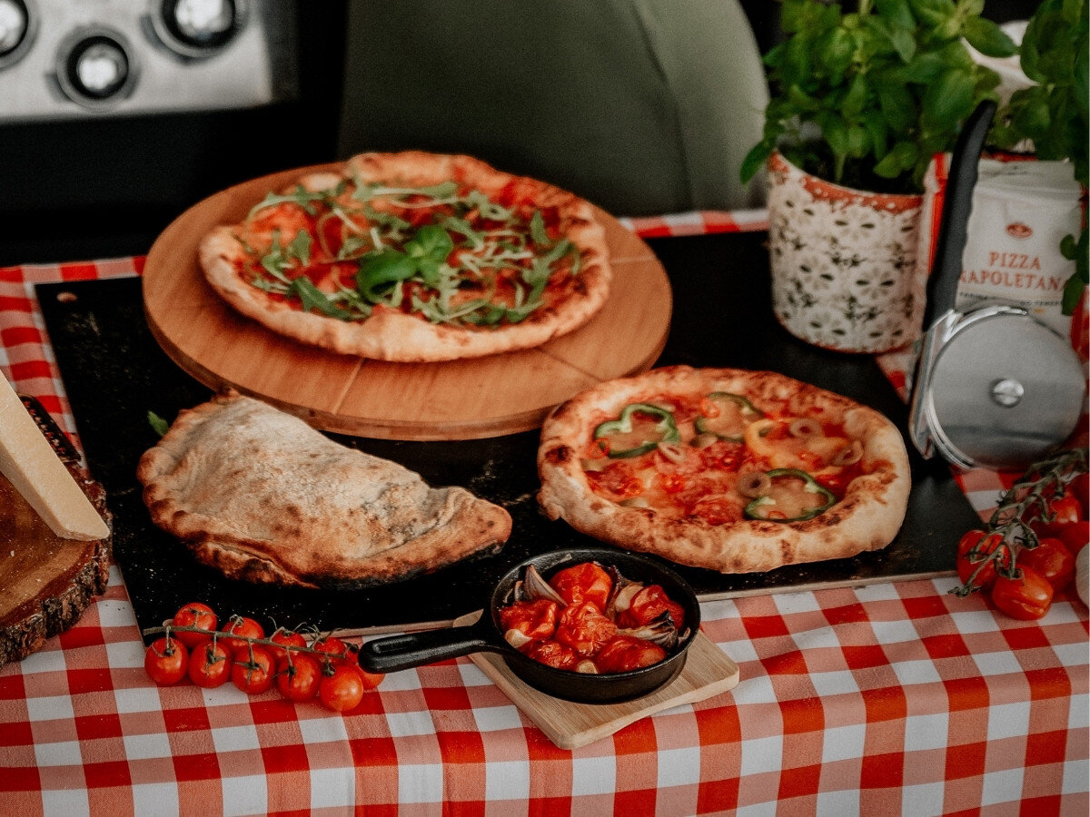 Nóż do pizzy BROIL KING 69810, nóż, focaccia, calzone, cięcie, Ręka kroi pizzę pepperoni za pomocą noża do pizzy Broil King na drewnianej desce.