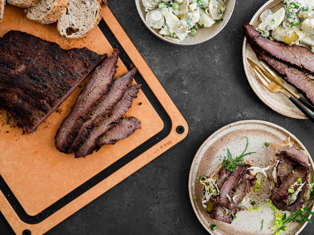 Deska do krojenia BROIL KING 68422, kuchnia, deska, grill, krojenie, Pokrojony pieczony schab na desce Broil King z sałatką, ziemniakami i dodatkami na ciemnym tle.