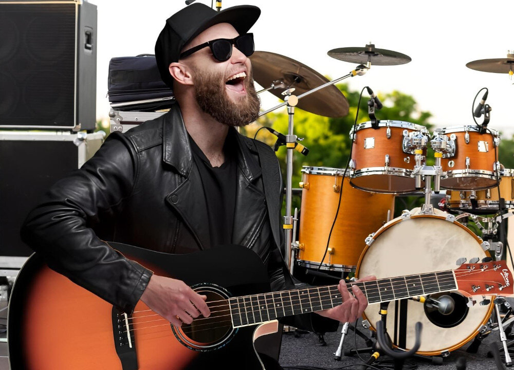 Gitara elektroakustyczna V-TONE Veag1 CE VS 4- Dla każdego poziomu gry, mężczyzna grający na gitarze, w tle perkusja