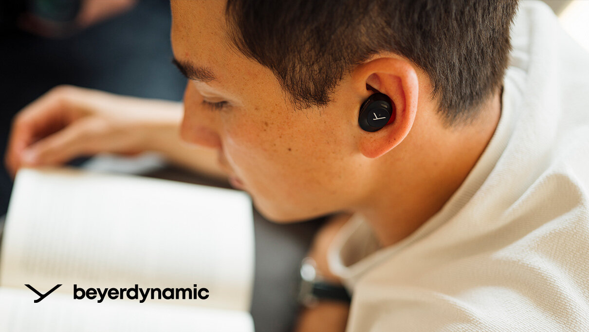 beyerdynamic AMIRON 300 osoba w słuchawkach w lewym dolnym rogu marka