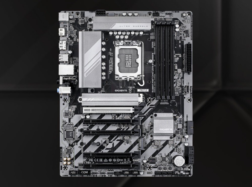 Płyta główna GIGABYTE B860 DS3H WiFi6E Widok z góry na płytę główną komputera w układzie pionowym. Centralny punkt zajmuje srebrne gniazdo procesora otoczone sekcją zasilania z radiatorami. Na dole znajdują się gniazda PCIe i złącza dla dysków