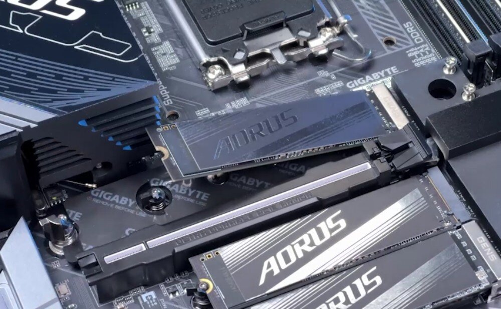 Płyta główna GIGABYTE B860 DS3H WiFi6E Zbliżenie na montaż dysku SSD M.2 z czarnym radiatorem 'AORUS' w gnieździe na płycie głównej. W tle widoczne są elementy gniazda procesora i banków pamięci