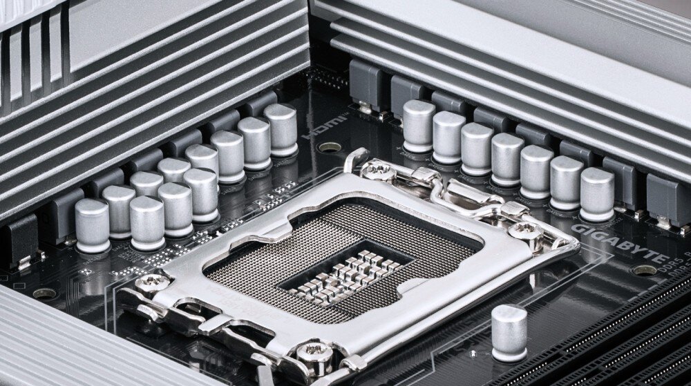 Płyta główna GIGABYTE B860 Gaming X WiFi6E Zbliżenie na gniazdo procesora płyty głównej otoczone srebrnymi elementami radiatora i kondensatorami, przeznaczenie, kompatybilność, procesory, sekcja zasilania