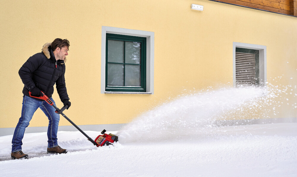 Odśnieżarka EINHELL GE-ST 36-40 Li E-Solo dom żółta ściana dom osoba odśnieża powierzchnię przed domem odśnieżanie bez wysiłku usuwanie śniegu skuteczność