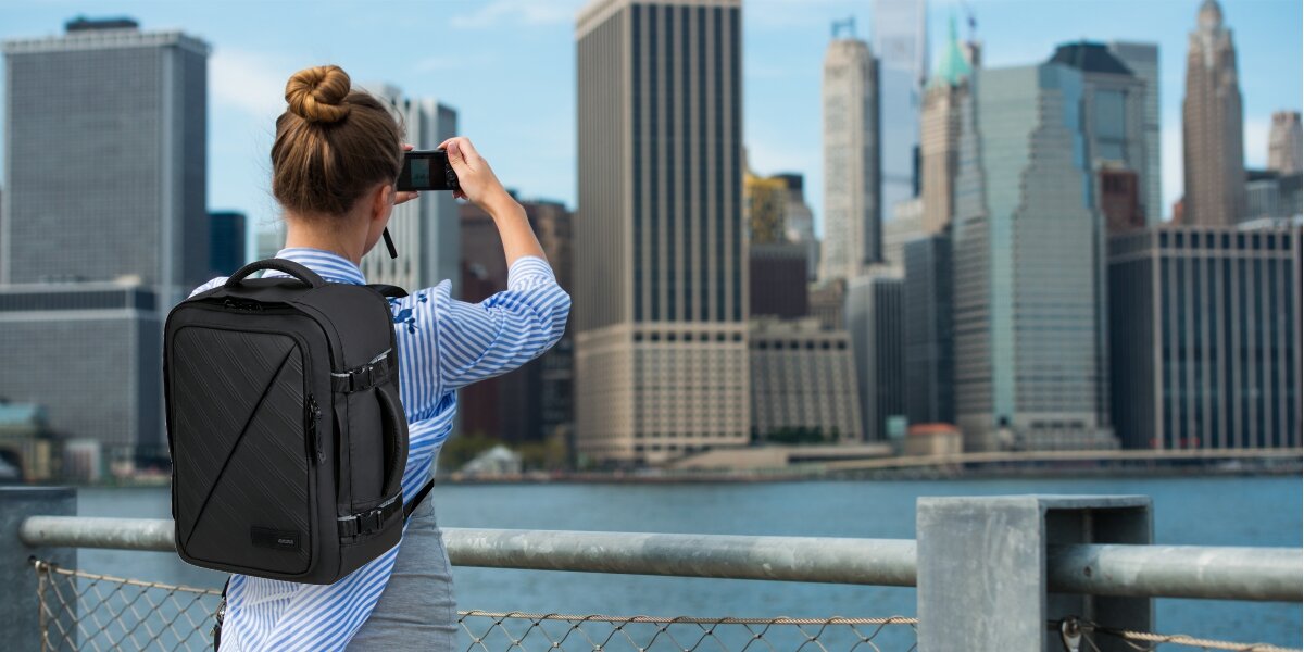 Plecak AMERICAN TOURISTER Take2Cabin Prime S Czarny, Funkcjonalny plecak, Kobieta z plecakiem na plecach patrzy przez lornetke