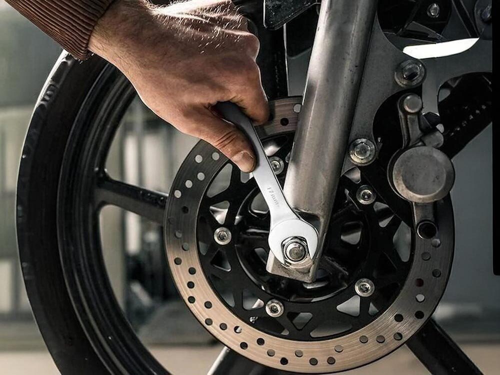 Zestaw kluczy płasko-oczkowych EXTRALINK 1291 (8 elementów), stal, chrom, trwałość, korozja, dłoń trzymając klucz dokręca śrubę koła motocykla