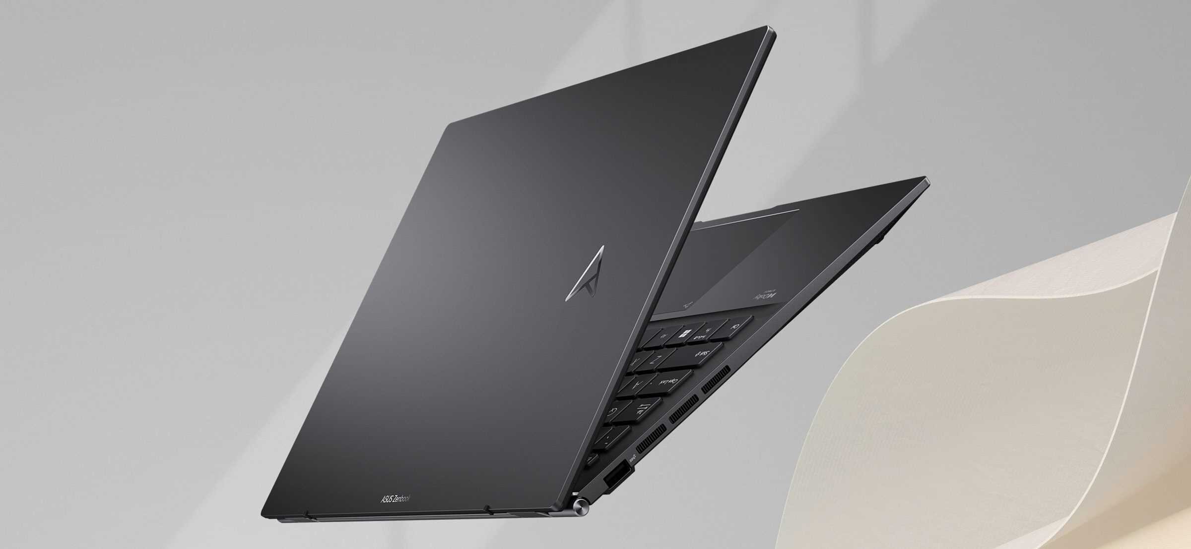 Laptop ASUS ZenBook UM3402 w kolorze czarnym, częściowo otwarty, widoczne białe klawisze i touchpad, jasne tło z delikatnym cieniem. - opis serii Zenbook 14. 