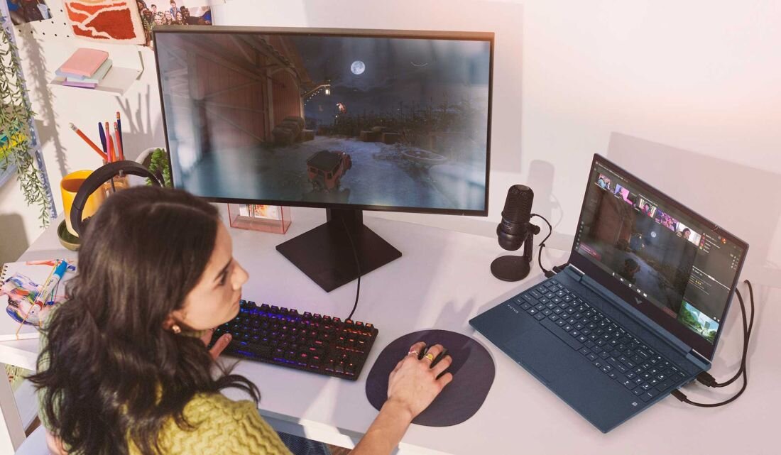 Laptop HP Victus 15 - Osoba grająca w grę wideo na laptopie, skupiona na ekranie, otoczona przyjemną atmosferą.