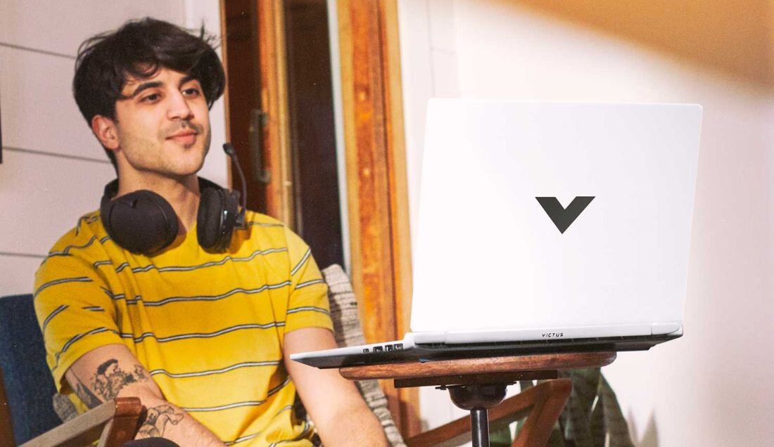 Laptop HP Victus 15 - Mężczyzna w słuchawkach, siedzący na krześle, korzysta z laptopa. Pojemna bateria, HP Fast Charge  