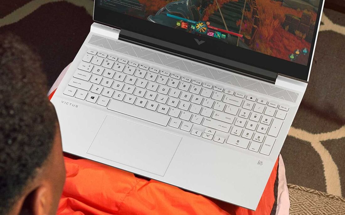 Laptop HP Victus 16 - Mężczyzna na kanapie korzysta z laptopa z podświetlaną klawiaturą RGB
