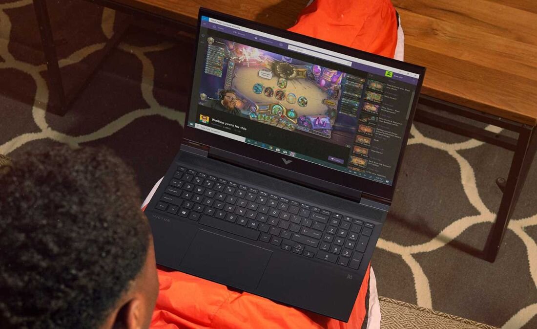 Laptop HP Victus 16 - Mężczyzna na kanapie korzysta z laptopa z podświetlaną klawiaturą RGB