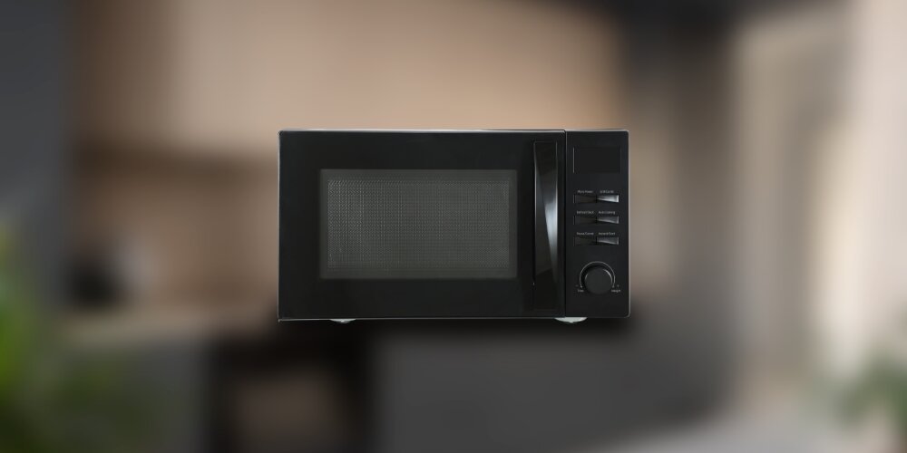 KUCHNIA MIKROFALOWA BEKO MGF23210B Kuchenka mikrofalowa Beko na rozmytym tle kuchni. Prosty, stalowy design