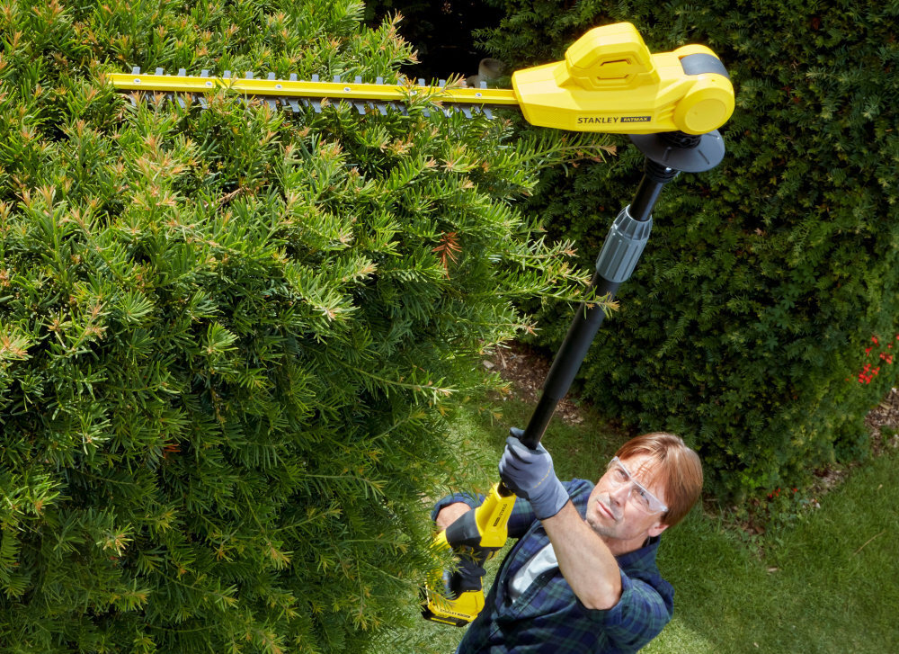 Nożyce do żywopłotu STANLEY SFMCPH845M1-QW 450mm 18V akumulatorowe ogród osoba przycina górę żywopłotu stojąc na ziemi trawnik kwiaty krzewy zasięg roboczy do 3,4 m zintegrowany wysięgnik o długości 1,8 m przycinanie wysokich i trudno dostępnych fragmentów żywopłotu, stojąc stabilnie na ziemi zwiększa bezpieczeństwo pracy przyspiesza cięcie górnych gałęzi pozwala w pełni kontrolować każdy ruch
