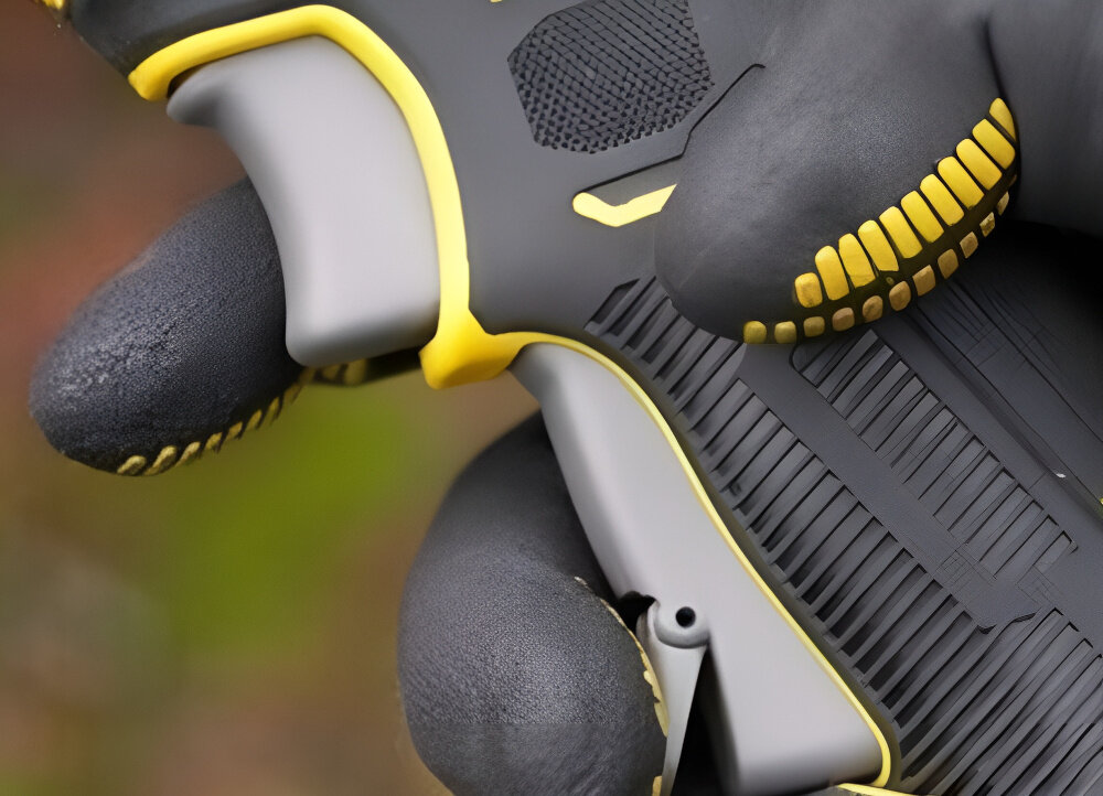 Sekator do gałęzi akumulatorowy STANLEY FatMax SFMCPP32M1-QW rozmazane tło zbliżenie na włącznik osoba trzyma palce na włączniku podwójny włącznik z blokadą ogranicza ryzyko przypadkowego uruchomienia narzędzia wymagane jest świadome użycie obu elementów sterujących kontrola nad urządzeniem bezpieczeństwo użytkownika