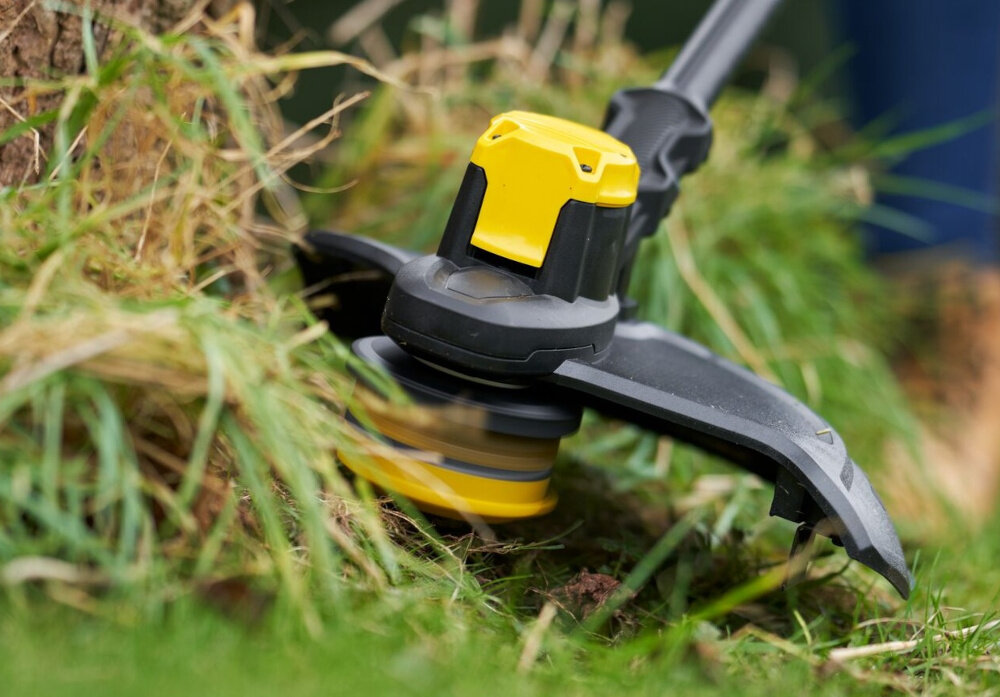 Podkaszarka akumulatorowa STANLEY SFMCSTB933B-XJ trawa zbliżenie na głowicę tnącą do precyzyjnego podkaszania trawy usuwania chwastów w miejscach trudno dostępnych praca bez przewodu