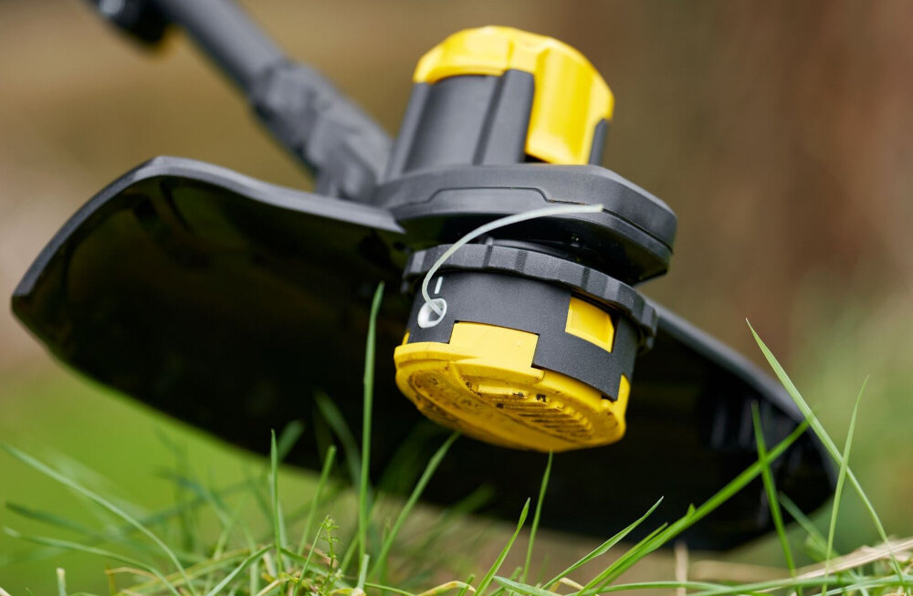 Podkaszarka akumulatorowa STANLEY SFMCSTB933B-XJ trawa zbliżenie na głowicę tnącą szerokość koszenia wynosząca 33 cm ogranicza liczbę przejść zmniejsza obciążenie użytkownika ułatwia utrzymanie porządku