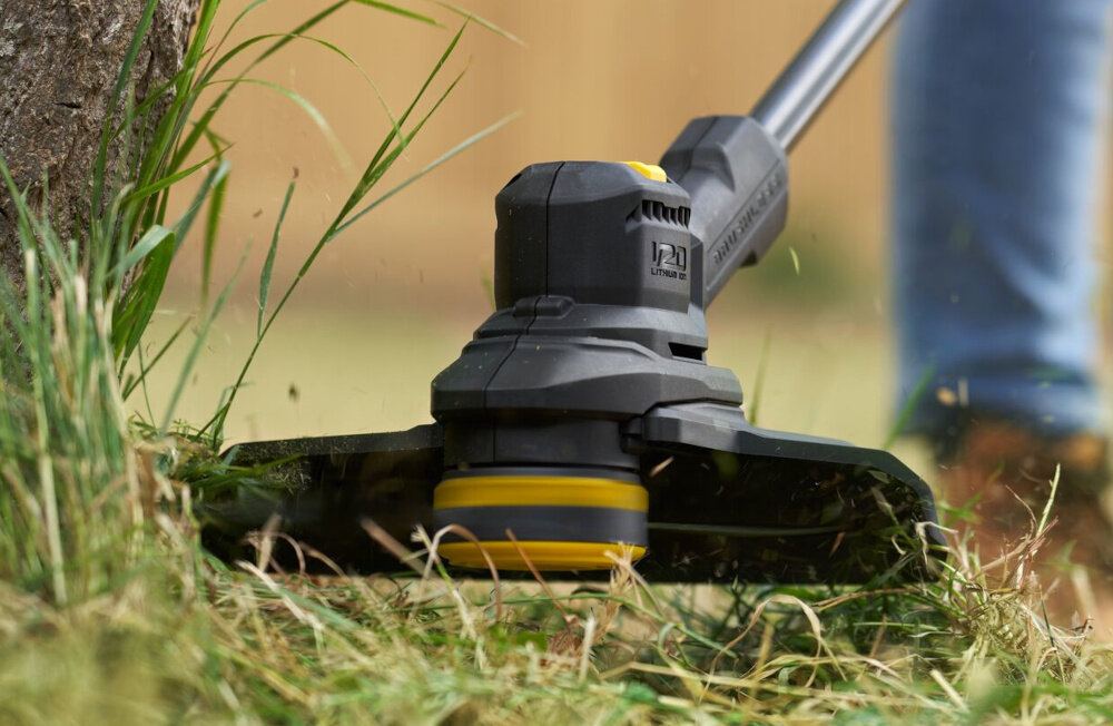 Podkaszarka akumulatorowa STANLEY SFMSTB930B-XJ ogród osoba tnie trawę wokół drzewa zbliżenie na moduł tnący wybór szerokości koszenia 28 lub 33 cm można dopasować sposób pracy do warunków w ogrodzie kontrolować tempo pracy dostosować narzędzie do aktualnych potrzeb