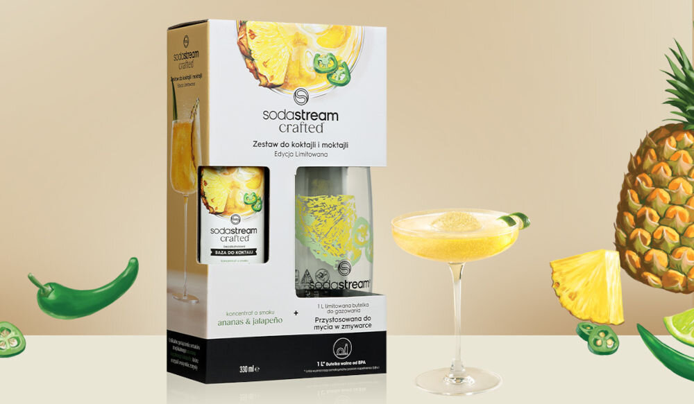 Zestaw upominkowy SODASTREAM Crafted Ananas & Jalapeño jasne tło rysunki ananasa paryczki opakowanie syrop butelka obok stoi napój w kieliszku bezalkoholowy tropikalna słodycz ananasa wyrazista ostrość jalapeño