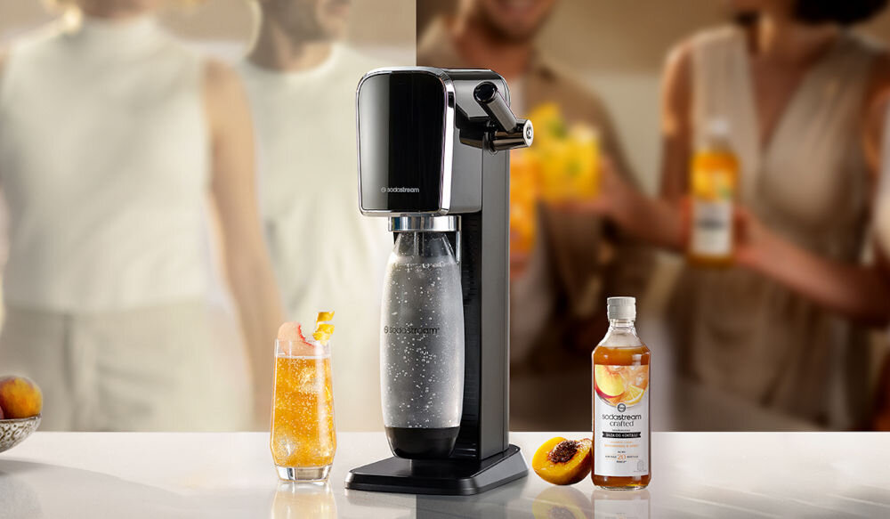 Zestaw upominkowy SODASTREAM Crafted Brzoskwinia & Imbir saturator syrop pomarańczowy napój w szklance brzoskwinia stworzenie czegoś wyjątkowego zainspirowanie się orzeźwiający moktajl w dłoni relaks harmonia oryginalne napoje podarowanie zestawu smak styl kreatywność